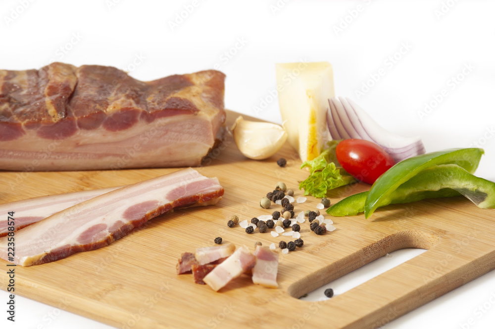 Smoked pork bacon slab - on cutting board with vegetables Smoked pork bacon slab - on cutting board with vegetables