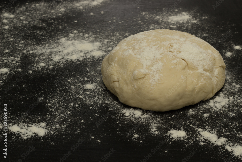 Circle of dough on a black background in flour Circle of dough on a black background in flour