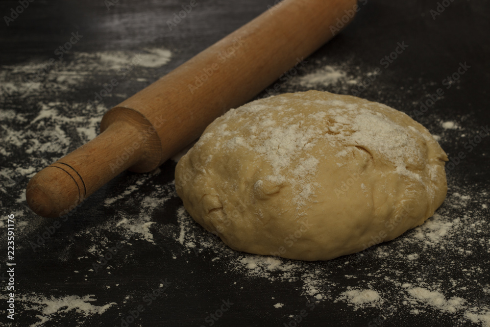 round dough and rolling pin on a dark background round dough and rolling pin on a dark background