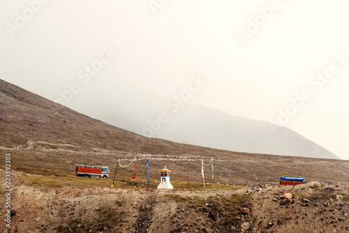 A small temple in the Himalayas mountains with trucks in the background