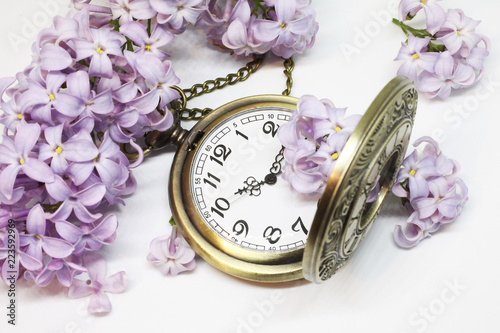 Pocket watch and beautiful lilac flower on white background photo