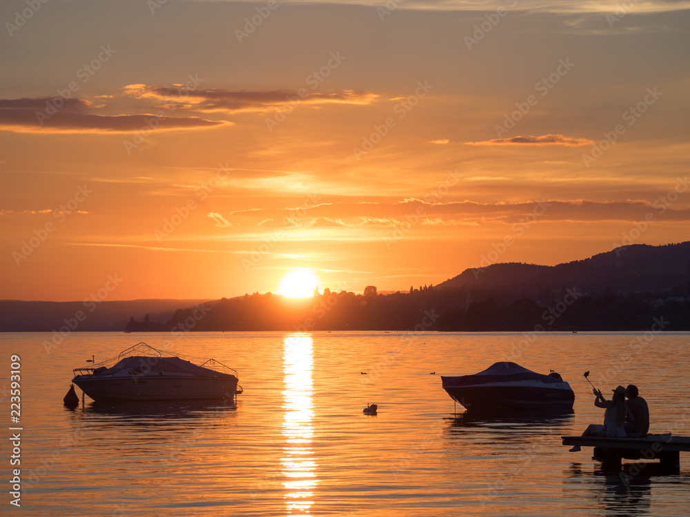 Sonnenuntergang mit Booten über dem Bodensee mit Selfie-Fotografen