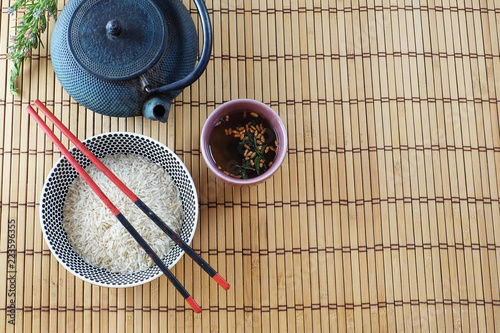 rice, tea bowl and traditionnal asian teapot on a bamboo mat