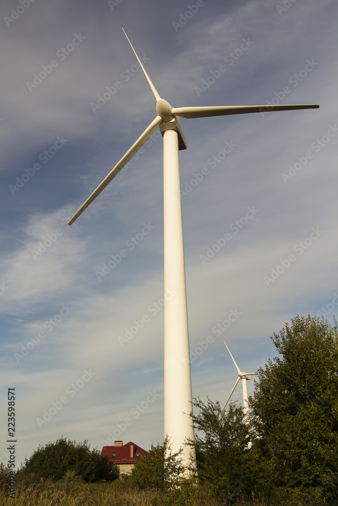 Windmill for electricity among the trees with the house. Windmill for electricity among the trees with the house.
