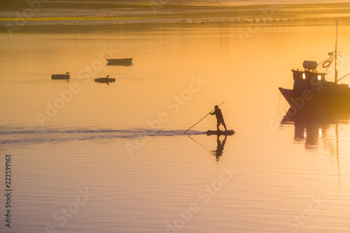 Fisherman silhouette. Sunrise in the harbour of Quellon in Chiloe Island. Patagonia in Chile photo