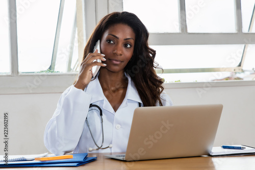 African american female doctor listening to patient at phone