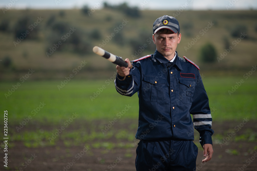 policeman in uniform with a rod in his hand on the background of rural landscape policeman in uniform with a rod in his hand on the background of rural landscape