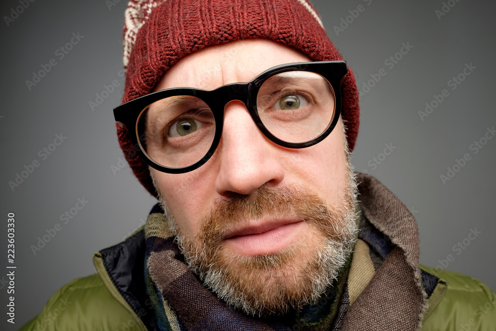 Close up portrait of middle aged europeam man in funny warm hat and glasses noticing hidden camera. Close up portrait of middle aged europeam man in funny warm hat and glasses noticing hidden camera.