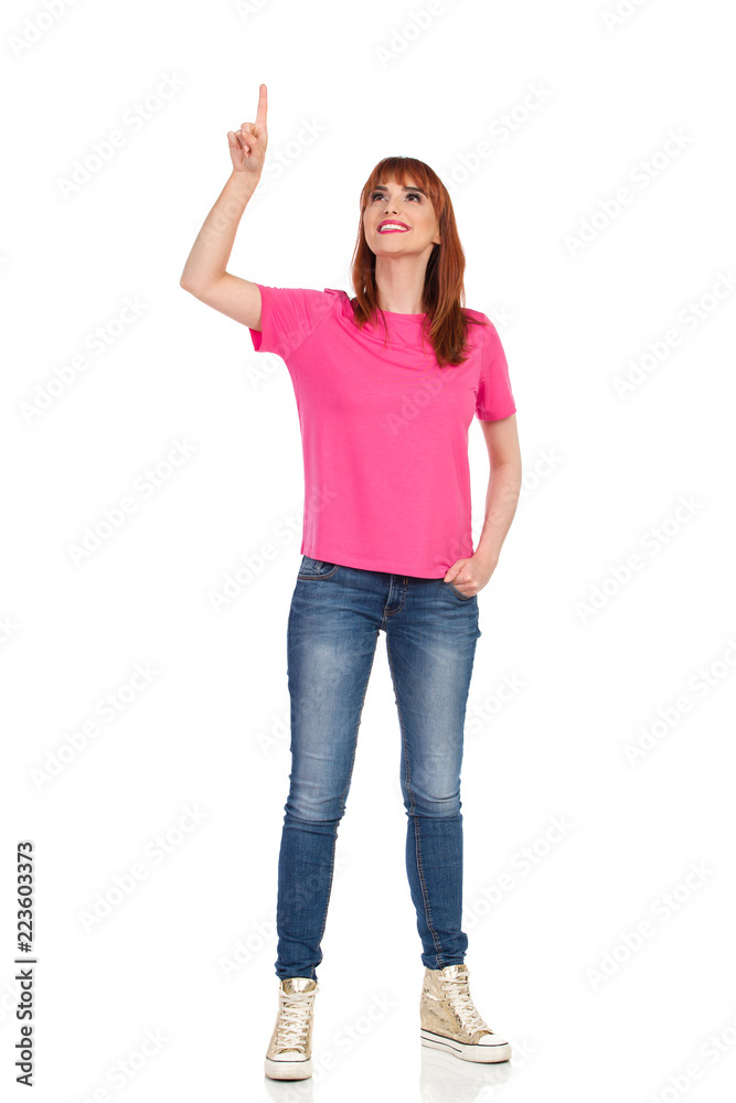 Young Woman Is Smiling, Looking Up And Pointing Young Woman Is Smiling, Looking Up And Pointing