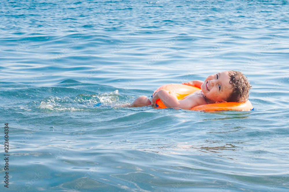 happy child bathes in the sea on an inflatable circle
