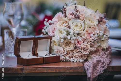 Close-up of bouquet with wedding rings on wooden table photo