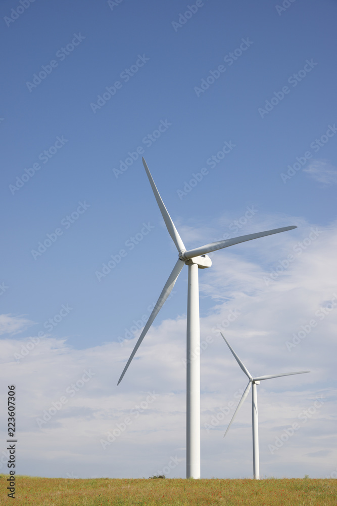 Windmills on field against blue sky during sunny day Windmills on field against blue sky during sunny day