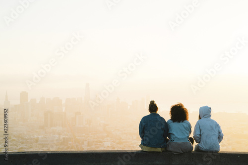 Rear view of friends looking at city during sunset photo