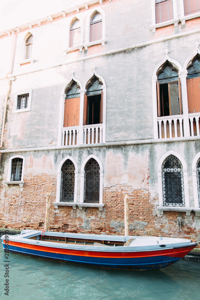 Old grey building and boat in venetian canal in Venice, Italy