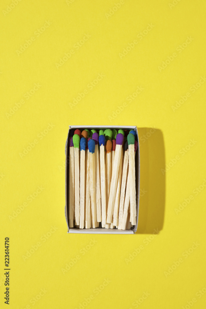 Overhead view of colorful matchsticks in box on yellow background Overhead view of colorful matchsticks in box on yellow background