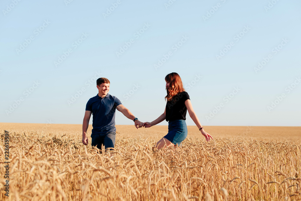 young loving couple in nature in summer on a background of field with oats