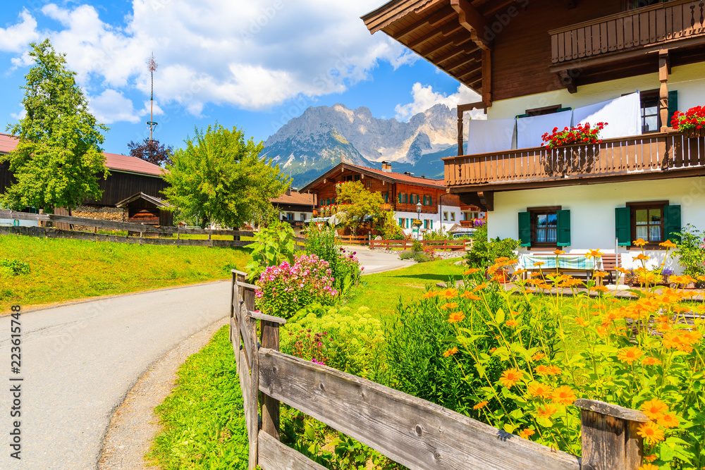 Road in Going am Wilden Kaiser village on sunny summer day and beautiful traditional houses decorated with flowers, Tyrol, Austria