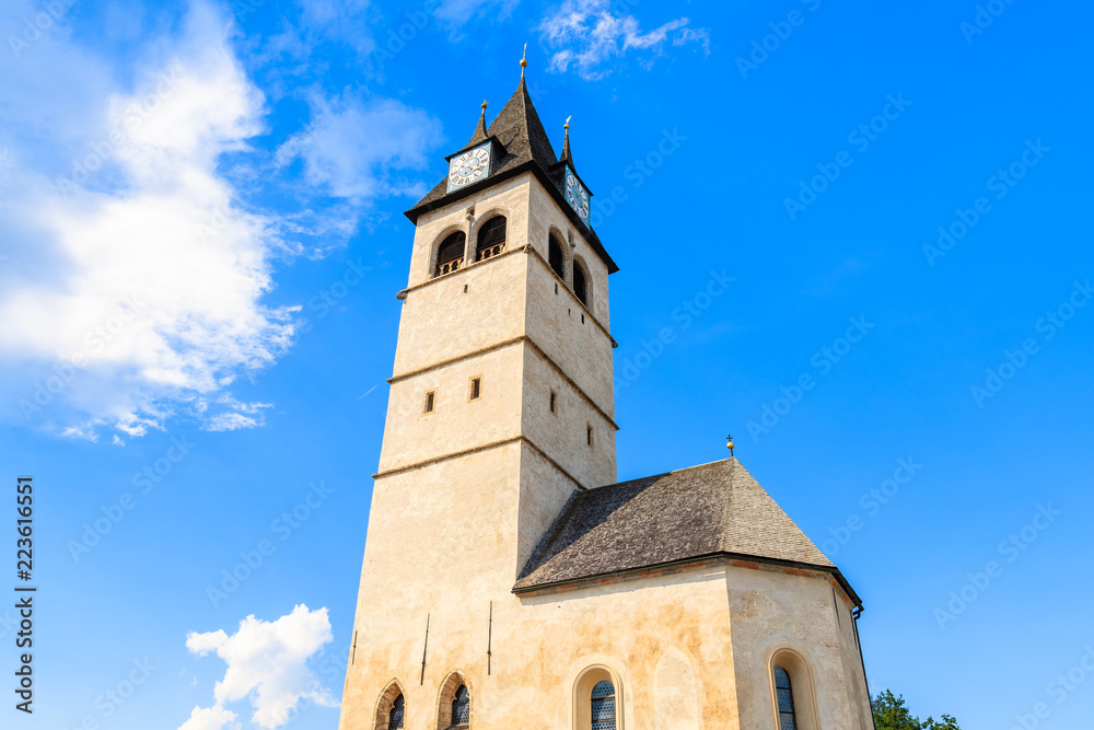 Fototapeta premium Church tower in Kitzbuhel town against sunny blue sky, Tirol, Austria