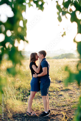 young loving couple in nature in summer on a background of green leaves