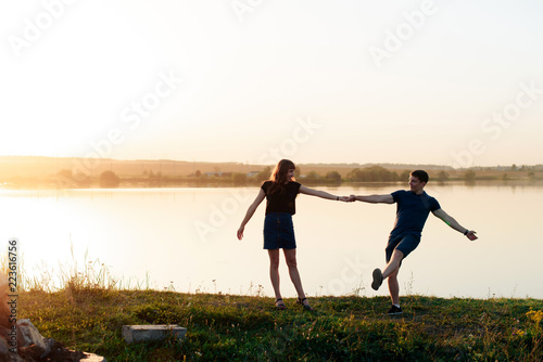 young enamored couple in nature in summer against the background of the river and sunset