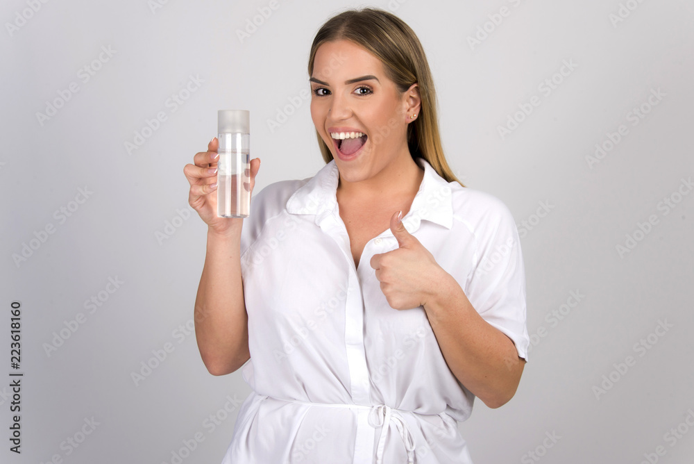 beautiful blond girl size plus model holding skin tonic micellar water in white skin dermatology concept beautiful blond girl size plus model holding skin tonic micellar water in white skin dermatology concept
