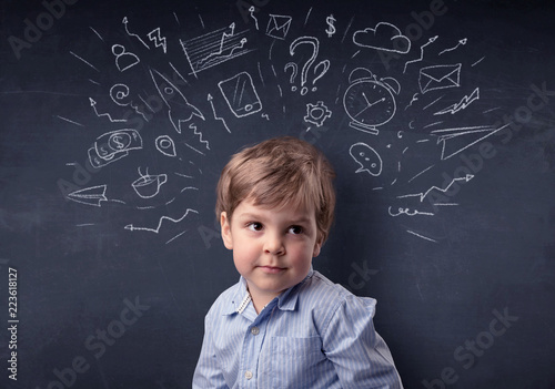 Smart little kid in front of a drawn up blackboard ruminate
