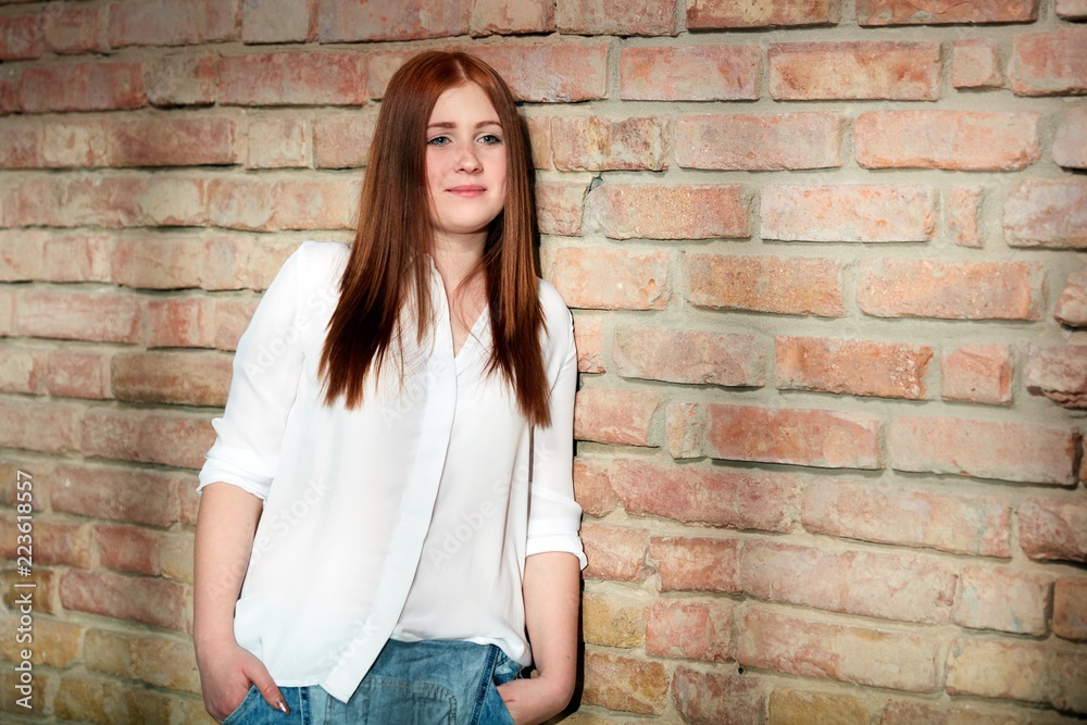 Ginger girl leaning against brick wall Ginger girl leaning against brick wall