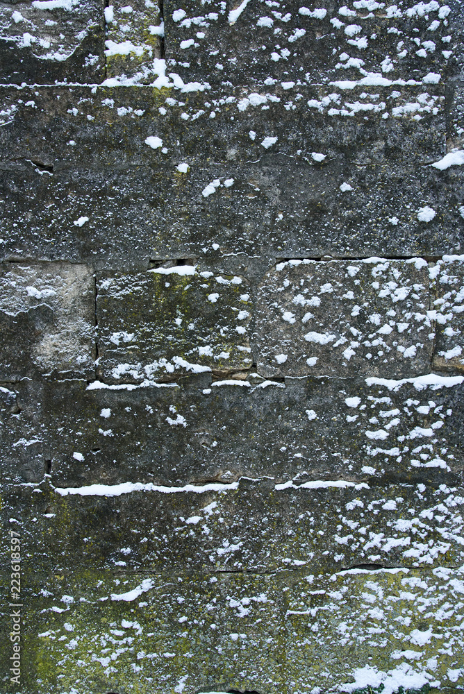 Obraz premium Medieval stone wall is covered with snow, design background with copy space, background on winter