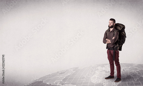 Handsome young man with a backpack on his back standing on a world map