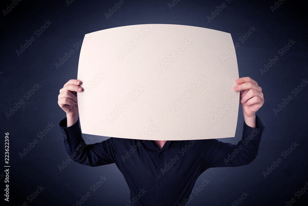 Young businessman hiding behind a blank piece of paper Young businessman hiding behind a blank piece of paper