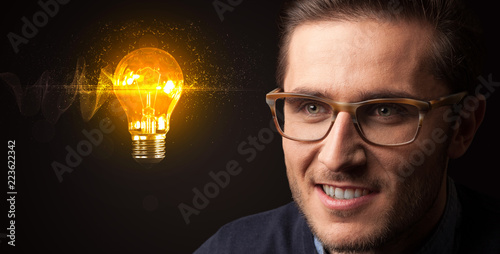 Portrait of a young businessman with a lightbulb next to him on a dark background