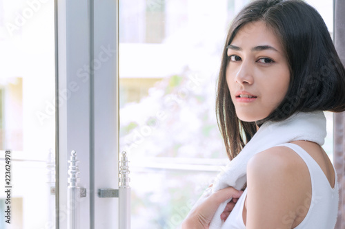 Attractive young woman 20s with towel at her neck in the morning standing beside the window while looking to the camera. Free Download Attractive young woman 20s with towel at her neck in the morning standing beside the window while looking to the camera. - GFXLoad