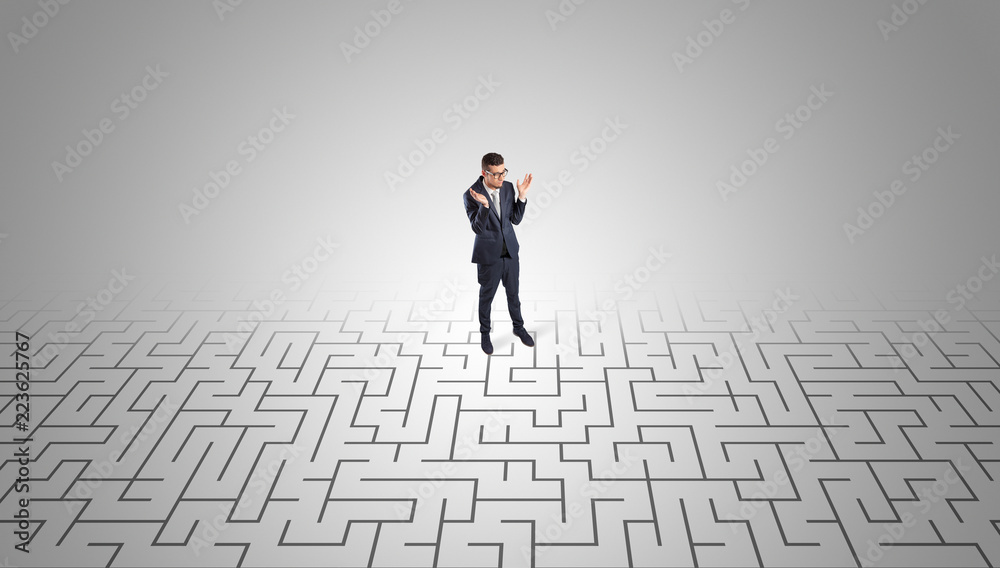 Elegant businessman looking for a solution in a middle of a maze
Elegant businessman looking for a solution in a middle of a maze