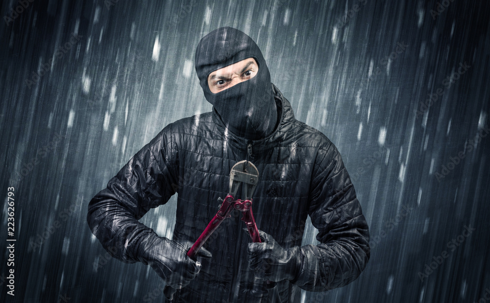 Naklejka premium Burglar in action in black clothes with rainy concept. 