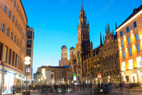 People walking at Marienplatz square and Munich city hall in night in Munich, Germany. Cafes, bars, shops and restaurants. Motion blurred people.