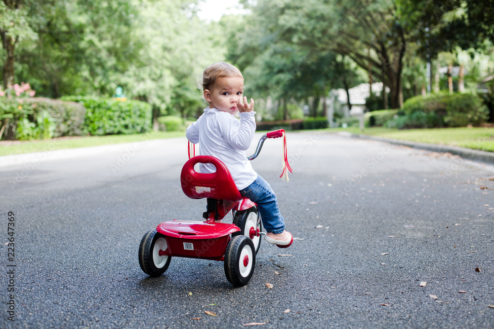 Young Child Toddler on Red Tricycle on a Neighborhood Street Looking at Camera Young Child Toddler on Red Tricycle on a Neighborhood Street Looking at Camera