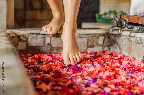 Attractive Young woman in bath with petals of tropical flowers and aroma oils. Spa treatments for skin rejuvenation. Alluring woman in Spa salon. Girl relaxing in jacuzzi with flower petals.