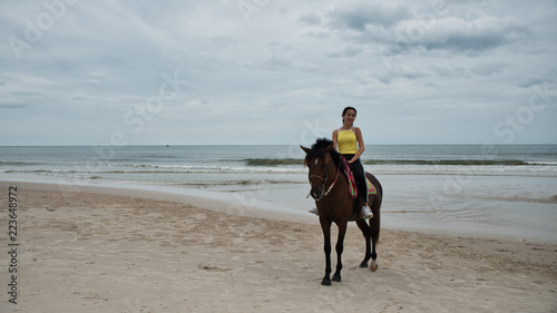 Young woman on beach with horse standing