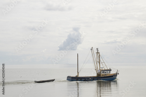 Fishing boat is emptying the nets, placed along the Aflsluitdijk in a calm peacfull IJsslemeer photo