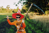 Halloween . Cheerful boy with a scythe in nature. Cheerful holiday
