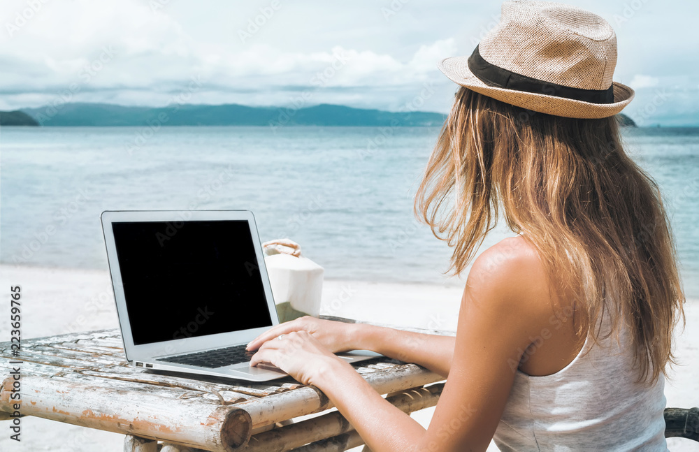 Young woman freelancer working on the beach