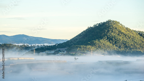 wonderful landscape of Da Lat city  early morning fog covering the city  far away is the green mountains  mist covered the greenhouse under the morning sun