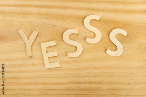 Yes, letters forming word on a wooden background with copyspace photo