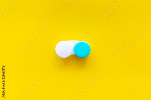 Improve vision concept. Contact lenses in container on yellow background top view copy space photo