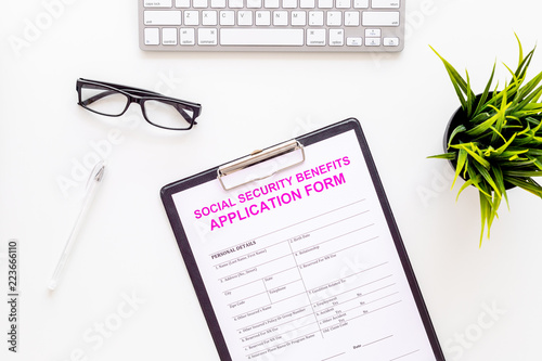 Social security benefits. Application form near pen and glasses on white background top view
