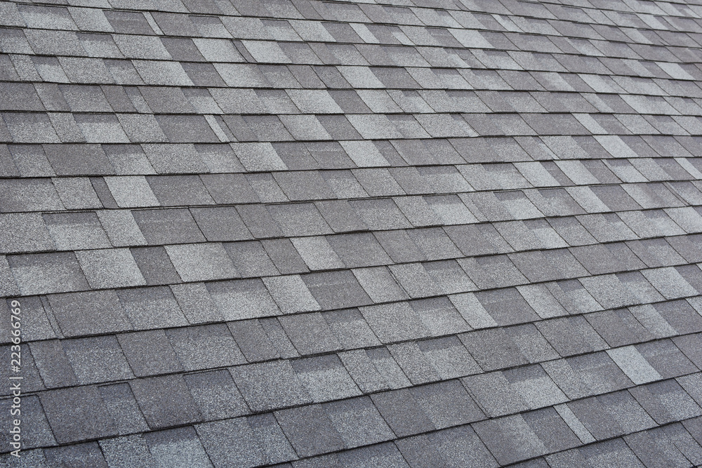 Grey asphalt roof shingles textured surface as abstract background.