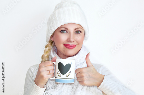finger up  in knitted things  in a hat and scarf  cup with tea  a cup of coffee