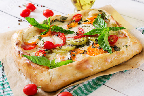 Mozzarella, tomatoes, basil savory pie on a white wooden background. Delicious food, appetizer in a mediterranean style.