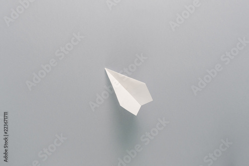 One flying paper plane over the grey background. Back to school and education concept. Plane as symbol of travelling and tourism.