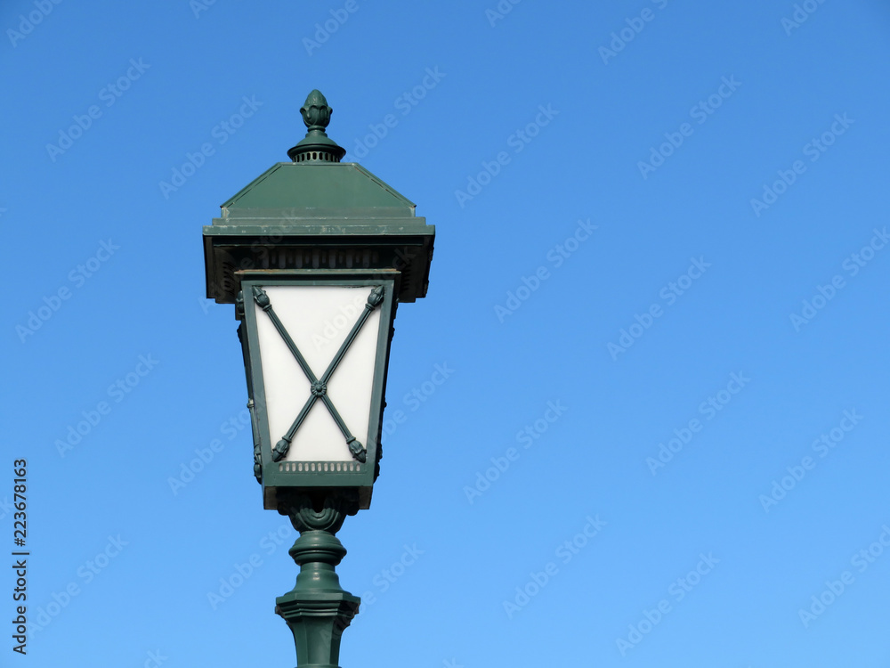Vintage street lamp isolated on clear blue sky. Street light, old fashioned green lantern